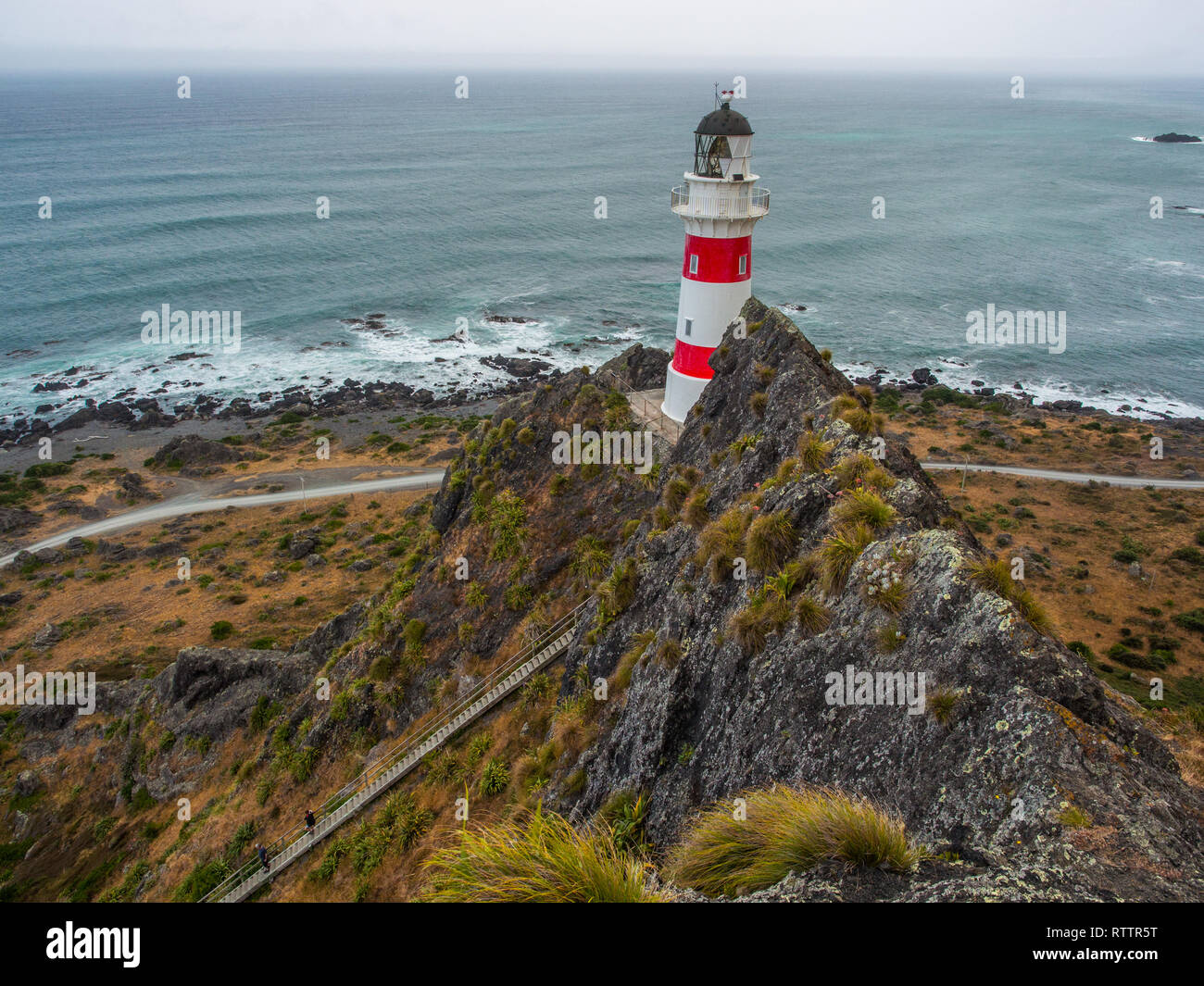 Guardando verso il basso su 2 persone, arrampicate ripide lunga fila di scale, fino a Cape Palliser faro, Palliser Bay, Wairarapa, Nuova Zelanda Foto Stock