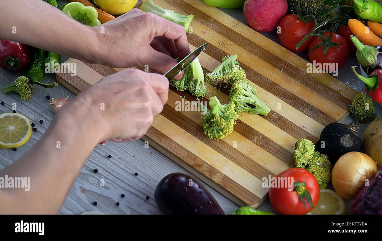 L uomo è il taglio di vegetali in cucina, affettare broccoli Foto Stock