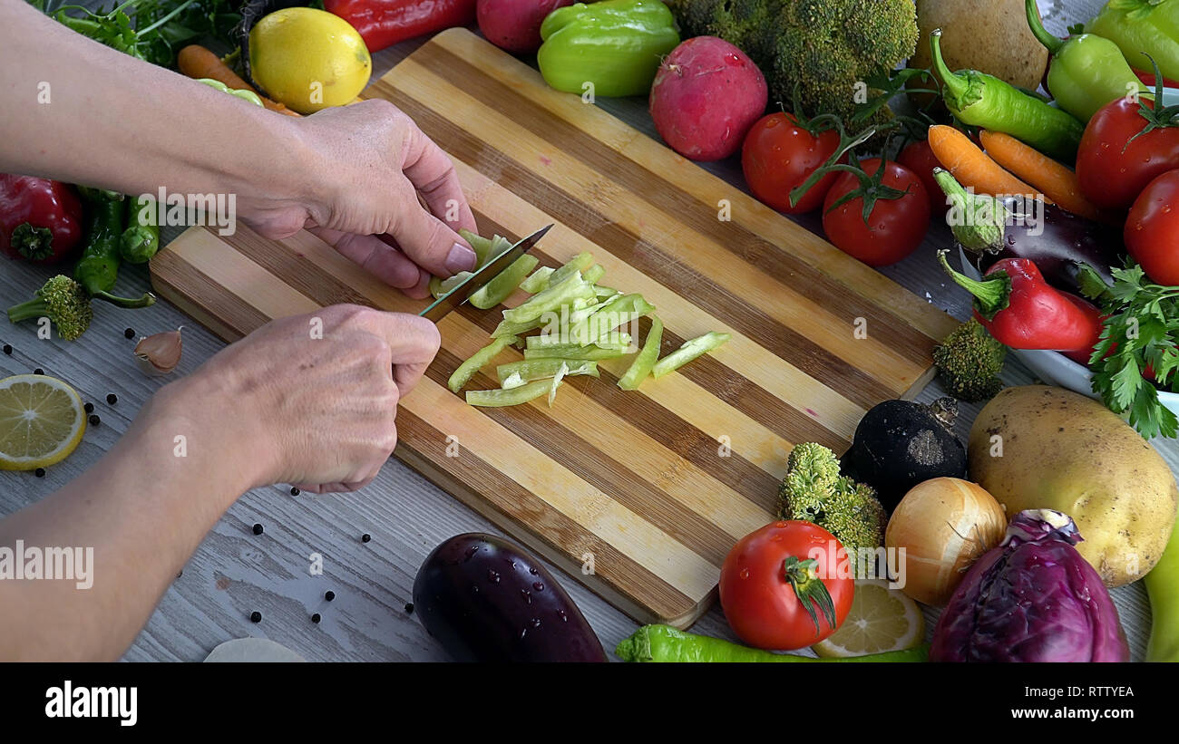 L uomo è il taglio di vegetali in cucina, affettare il peperone verde Foto Stock