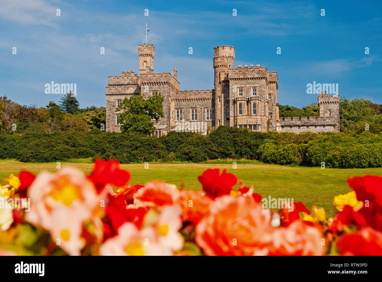 Il castello di Lews a Stornoway, Regno Unito con rose sfocata in primo piano. Castello con motivi verde sul cielo blu. Storica architettura e design. Punto di riferimento e di attrazione. Vacanze estive sull isola. Foto Stock