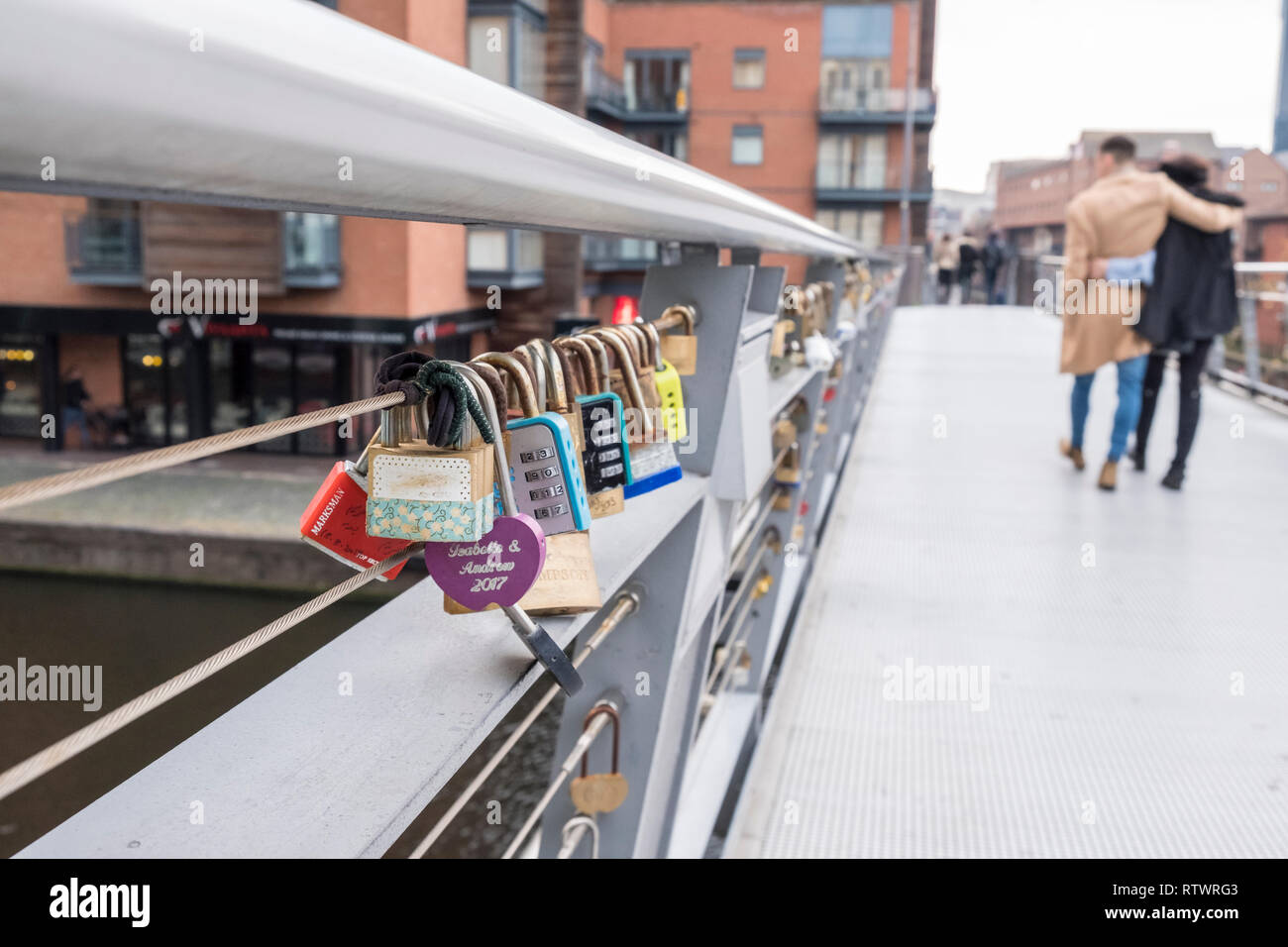 Abbracciando giovane a piedi passato Lovelocks o amore blocca bloccato su di un ponte a Birmingham, Inghilterra, GB, UK. Foto Stock