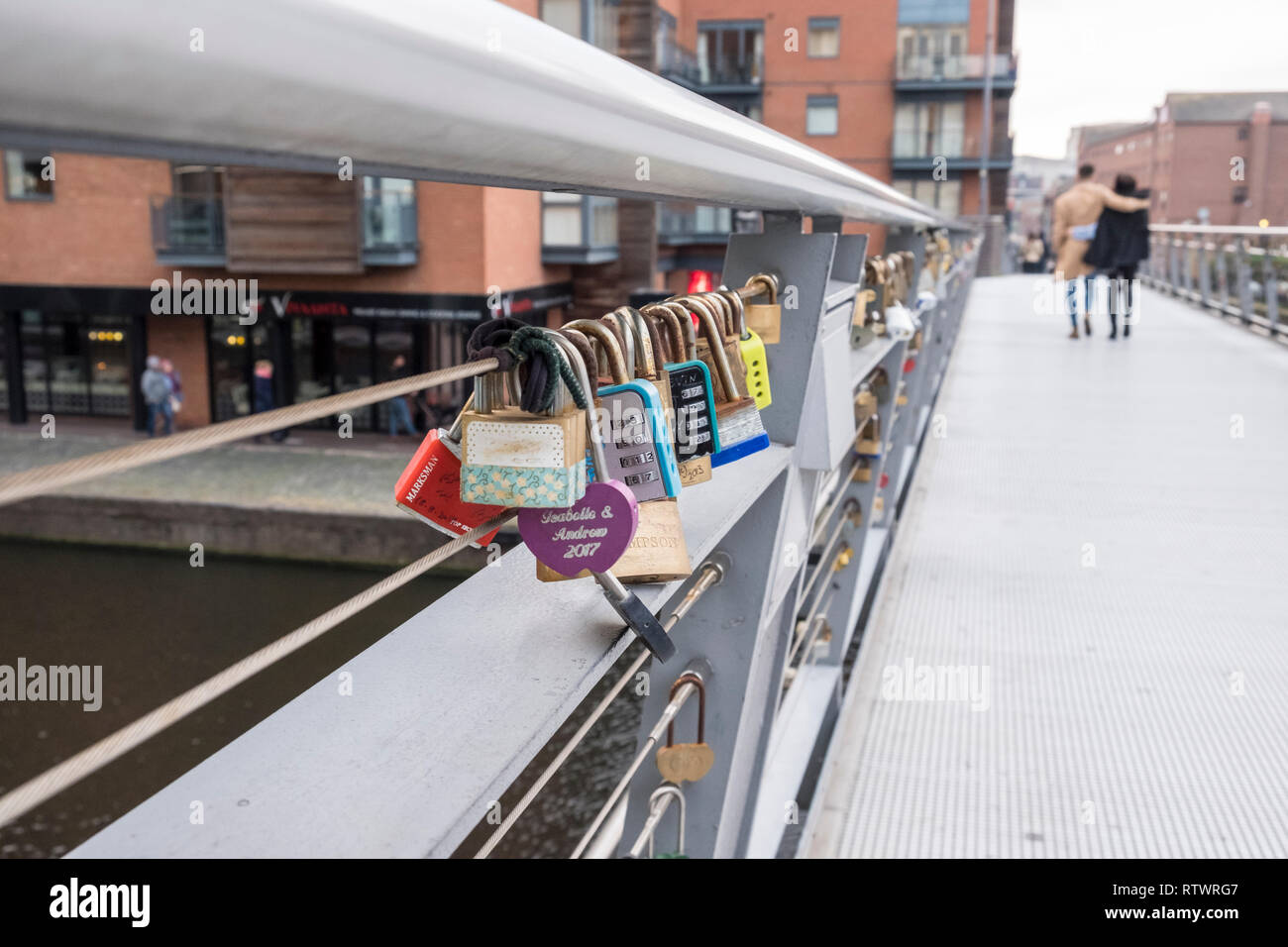 Abbracciando giovane a piedi passato Lovelocks o amore blocca bloccato su di un ponte a Birmingham, Inghilterra, GB, UK. Foto Stock
