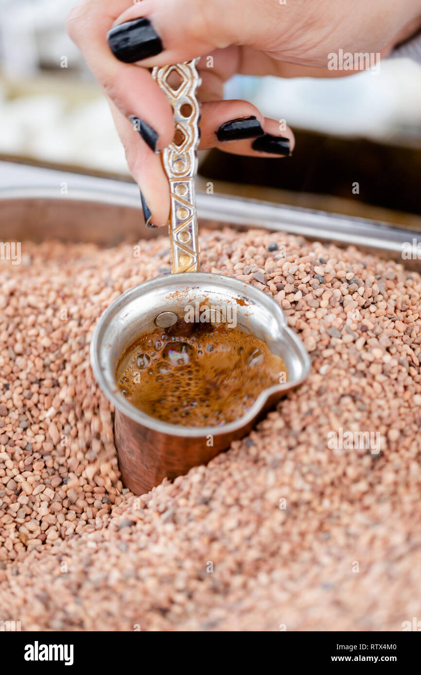 Tradizionale turca, arabo caffè servito in piccole tazze di rame nella calda sabbia. Immagine ravvicinata Foto Stock