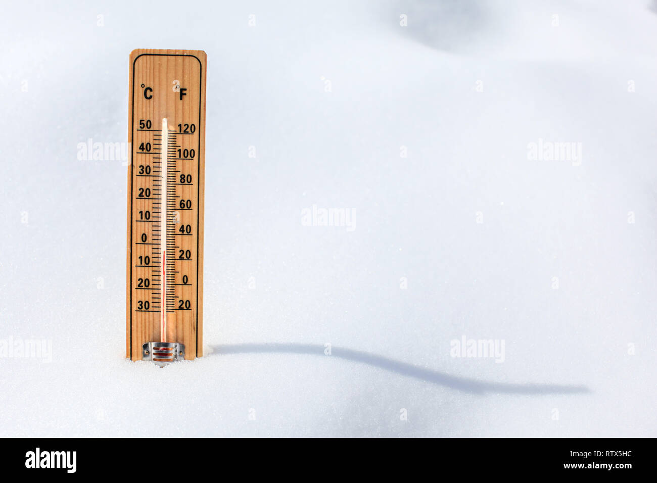 Termometro in legno in piedi nella neve, che mostrano una bassa temperatura, spazio per il testo a destra. L'inverno prossimo concetto. Foto Stock