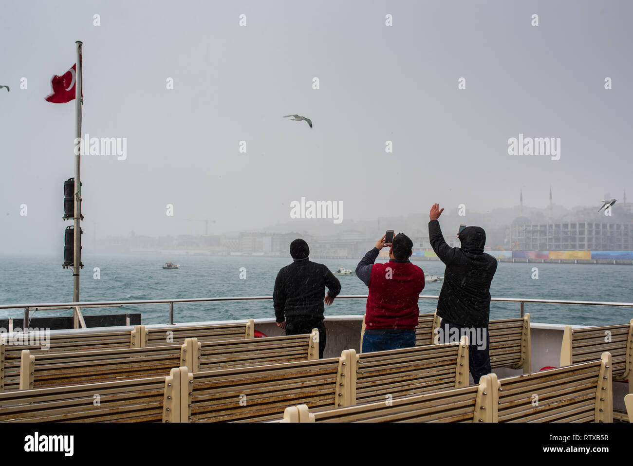 ISTANBUL, TURCHIA; inverno a Istanbul. Gli uomini in nevicata sul traghetto passeggeri Foto Stock