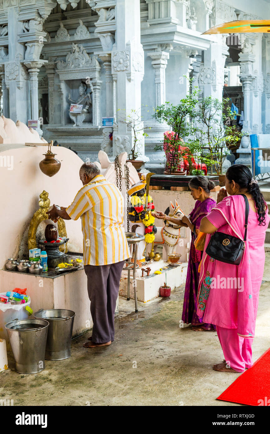 Un adoratore si versa acqua sulla Shiva Lingam entrando il Hindu Sri Maha Muneswarar tempio, Kuala Lumpur, Malesia. Foto Stock