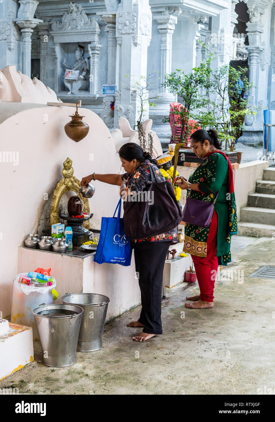 Un adoratore si versa acqua sulla Shiva Lingam entrando il Hindu Sri Maha Muneswarar tempio, Kuala Lumpur, Malesia. Foto Stock