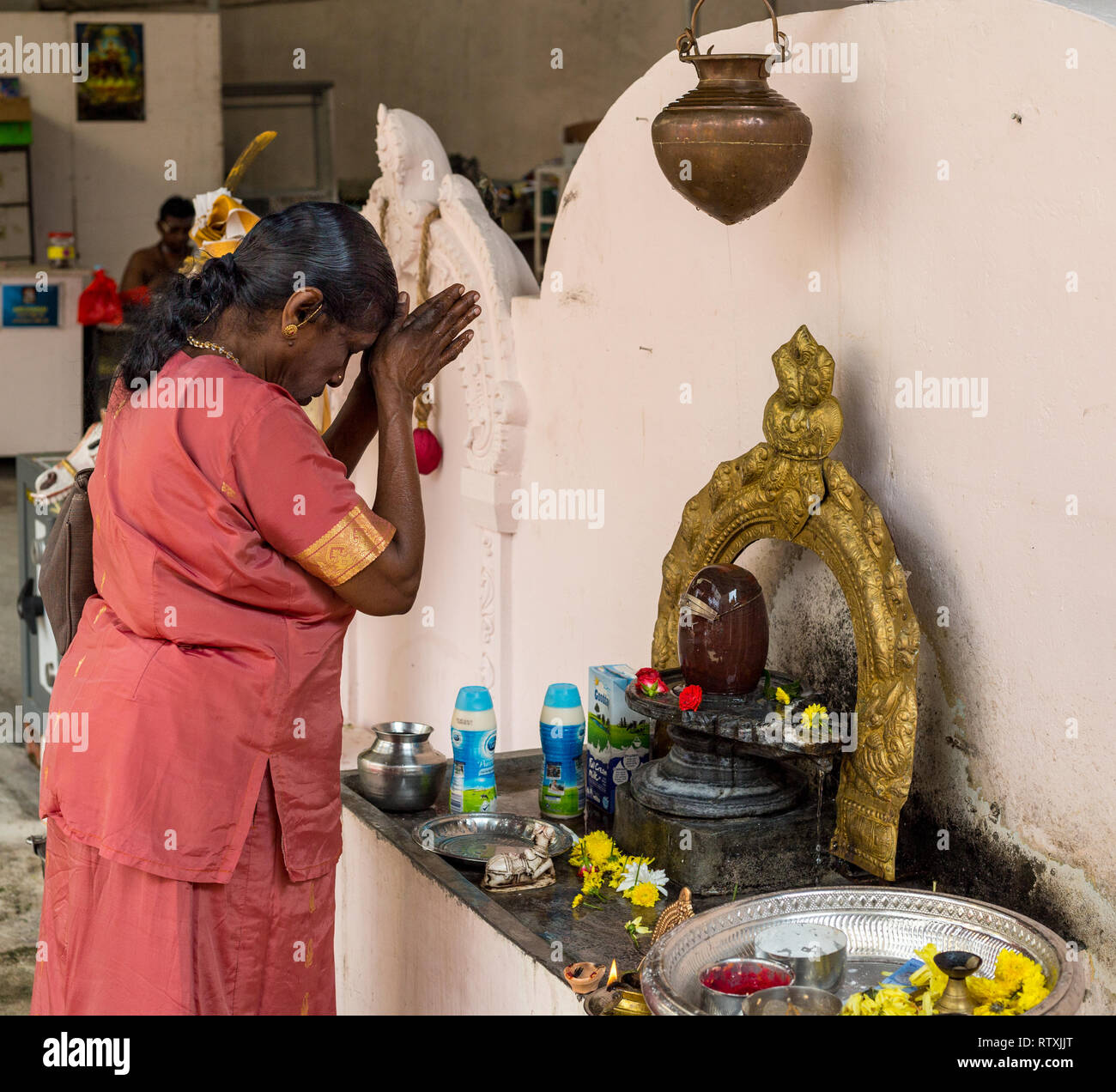 Donna orante davanti di Shiva Lingam prima di entrare Hindu Sri Maha Muneswarar tempio, Kuala Lumpur, Malesia. Foto Stock
