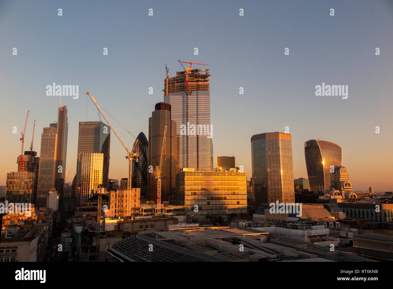 Un drammatico City of London skyline con gli alti edifici immersi nella luce dorata Foto Stock