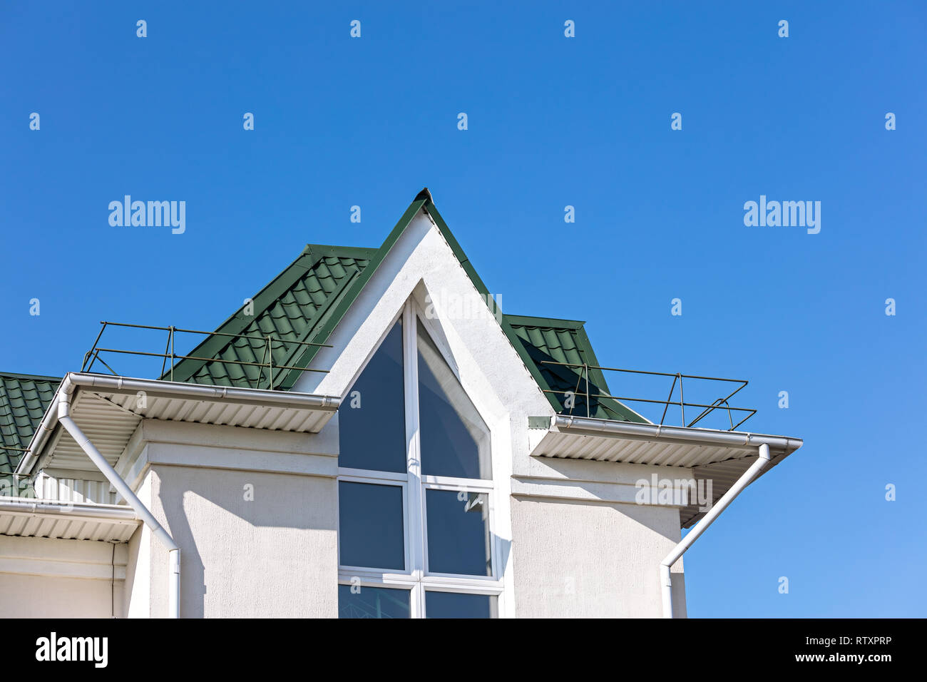 Il tetto della casa di nuova costruzione con metallo bianco drainpipe sistema contro il cielo blu sullo sfondo Foto Stock