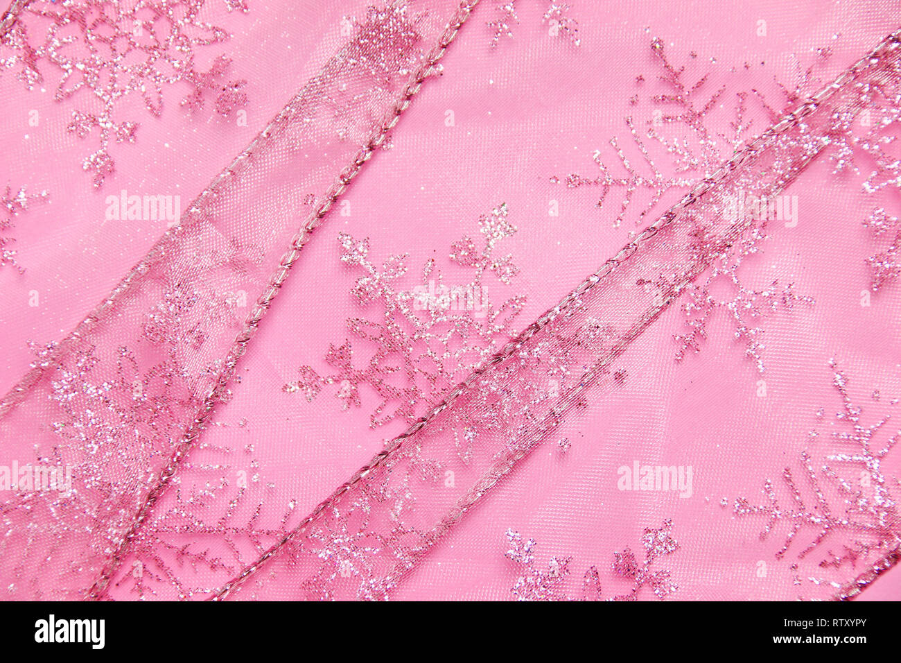 Un abstract texture di sfondo close up dettaglio in un Natale nastro rosa glitter con i fiocchi di neve Foto Stock