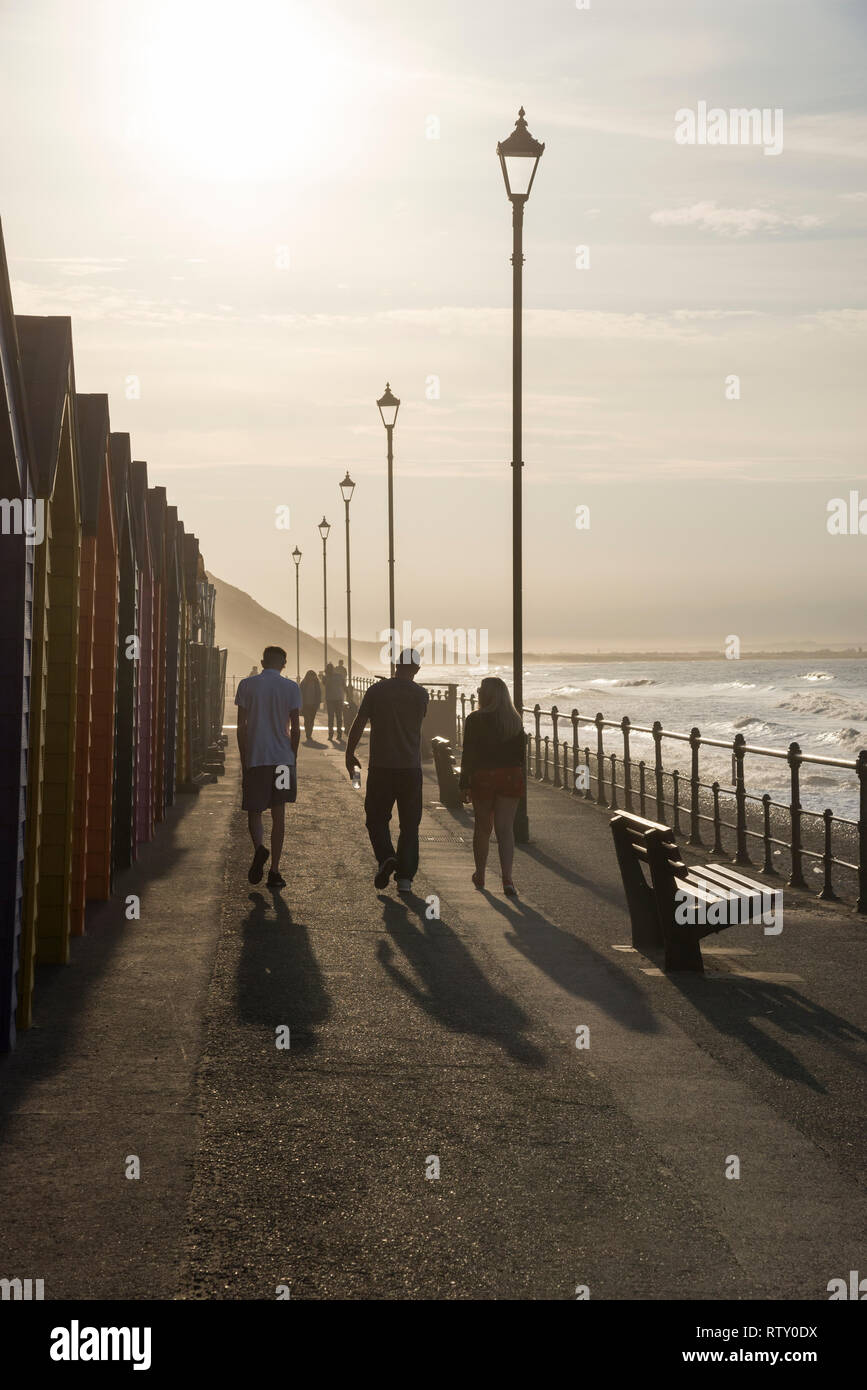 La gente che camminava nel tardo pomeriggio di sole sul lungomare a cambs, North Yorkshire, Inghilterra. Foto Stock