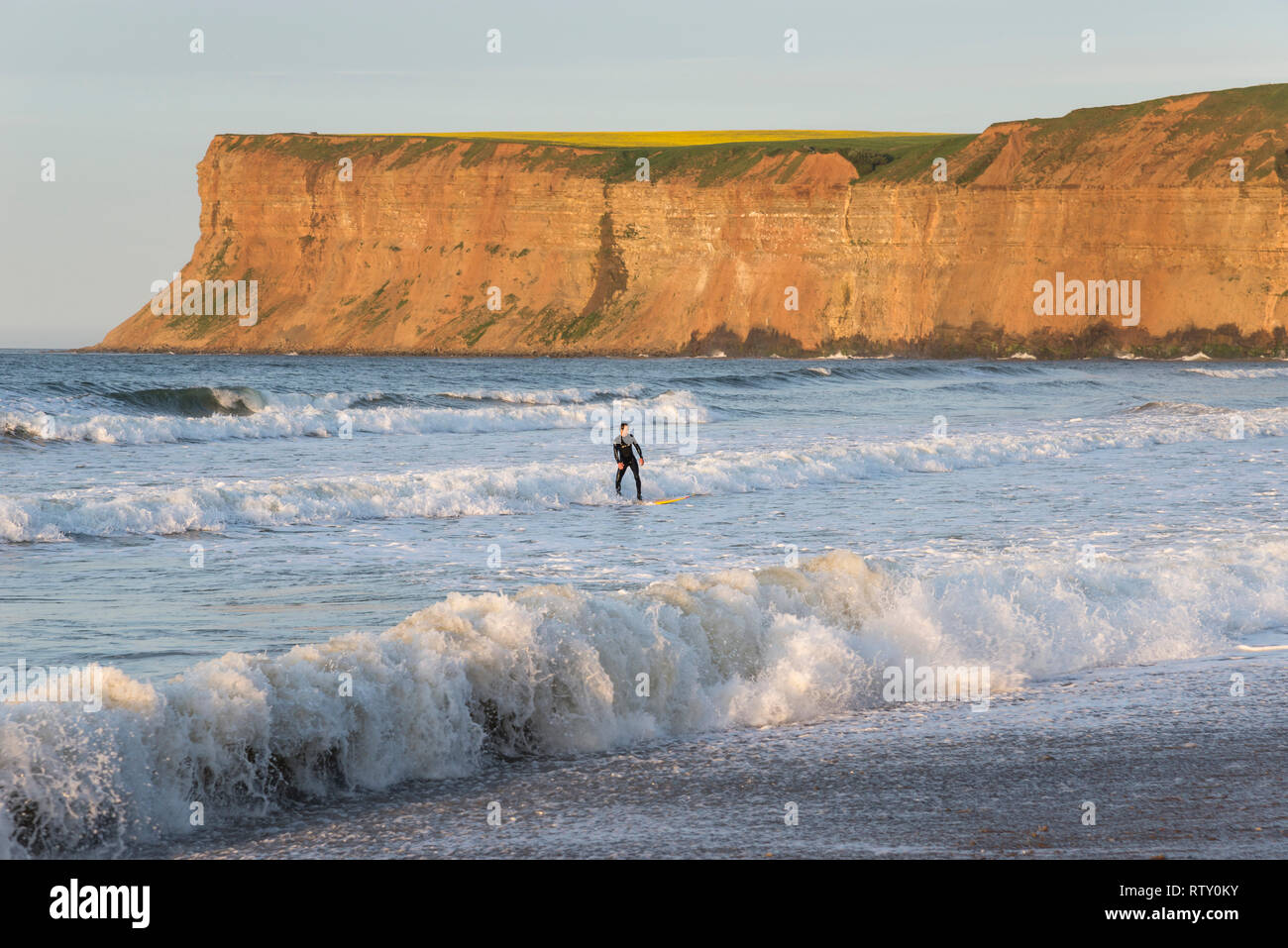 Surfer a cambs, North Yorkshire, Inghilterra. Huntcliff in background. Foto Stock