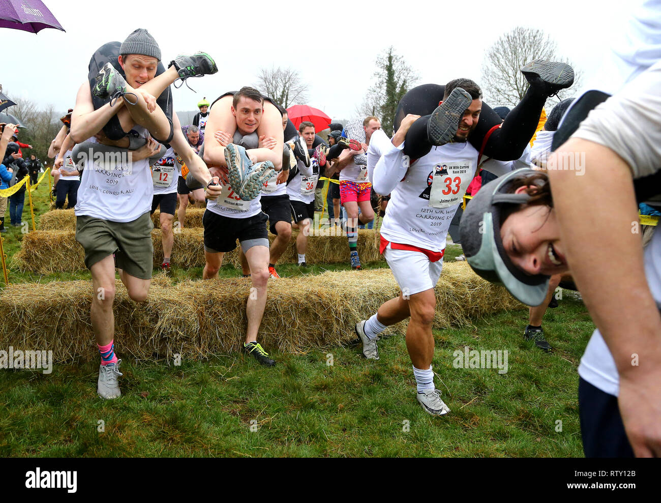 I concorrenti prendere parte all'annuale Moglie del Regno Unito che trasportano gara al Nower a Dorking, Surrey. Foto Stock