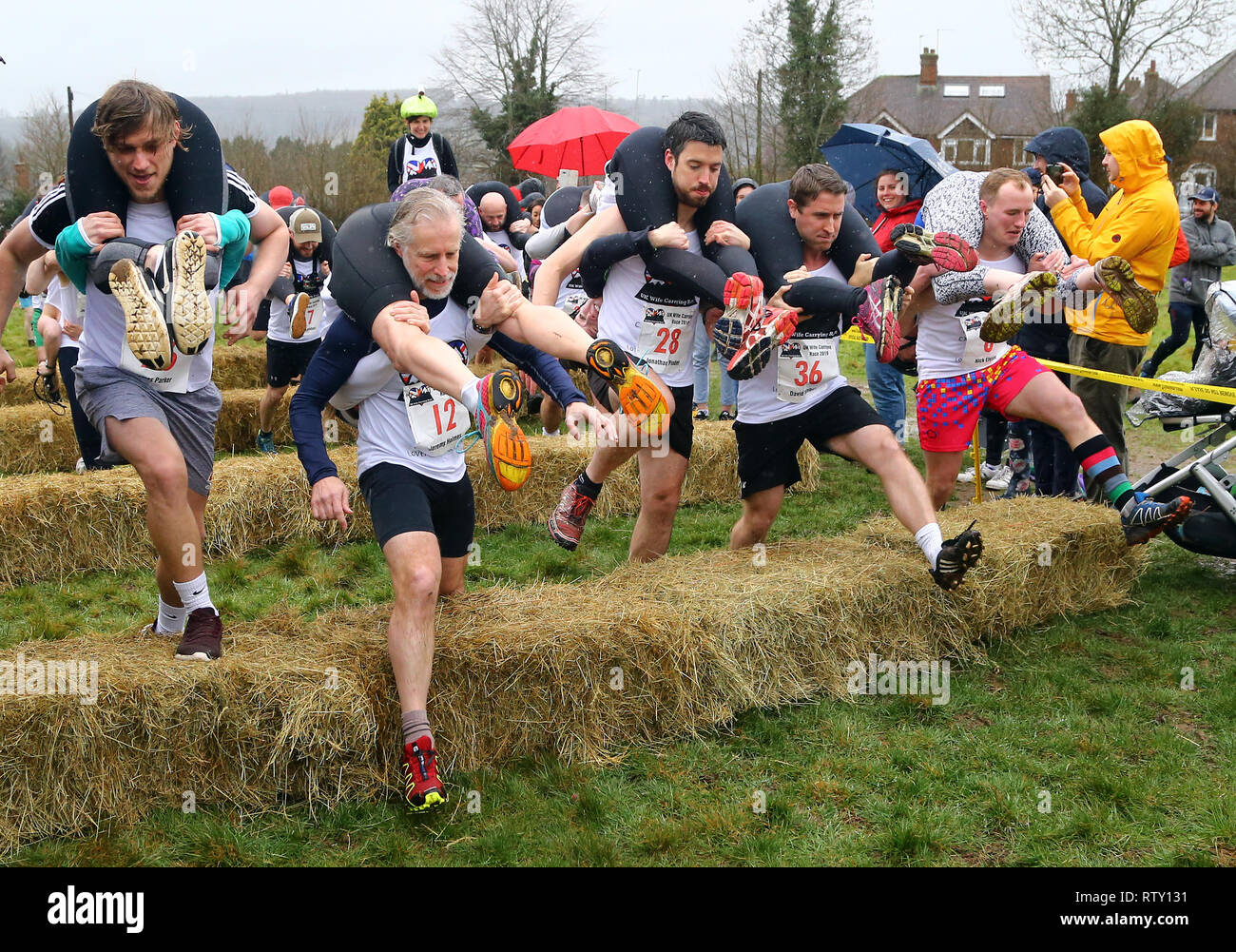 I concorrenti prendere parte all'annuale Moglie del Regno Unito che trasportano gara al Nower a Dorking, Surrey. Foto Stock