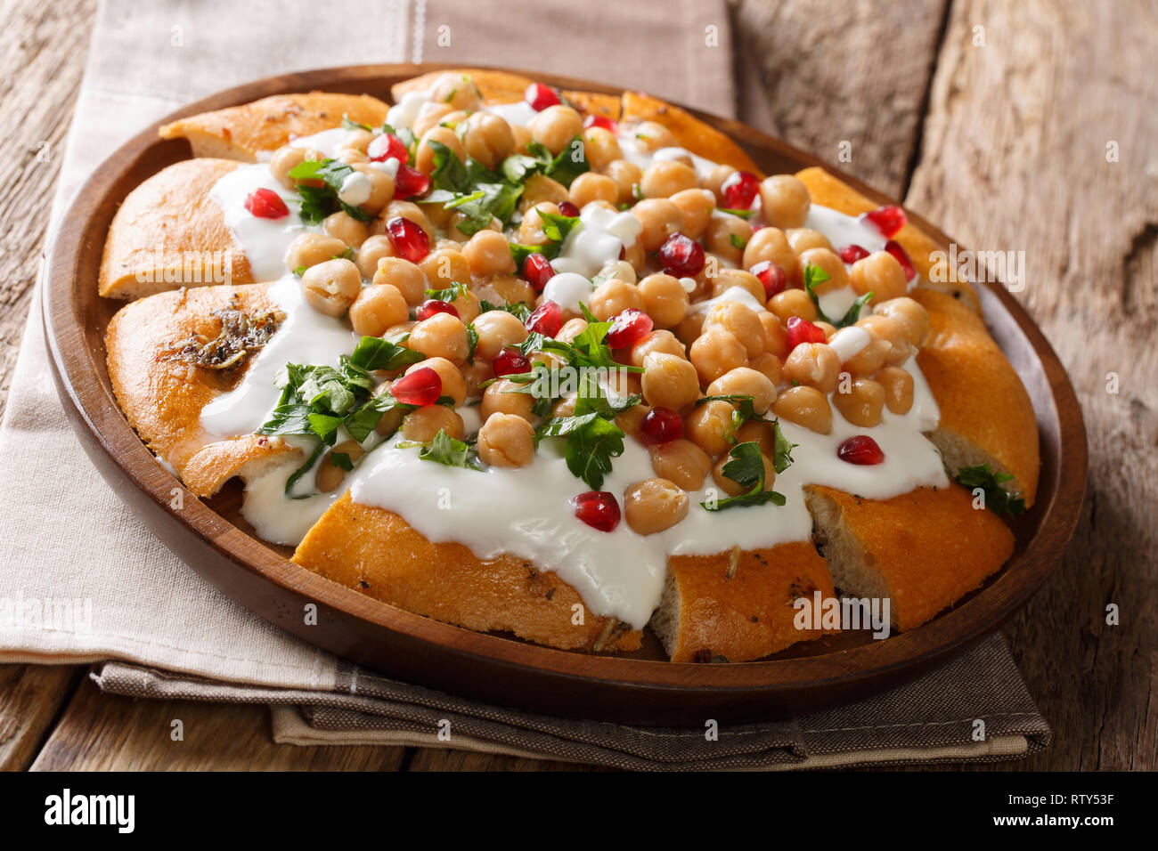 Cibo vegetariano da pita con ceci, lo yogurt e i semi di melograno close-up su una piastra sul tavolo orizzontale. Foto Stock