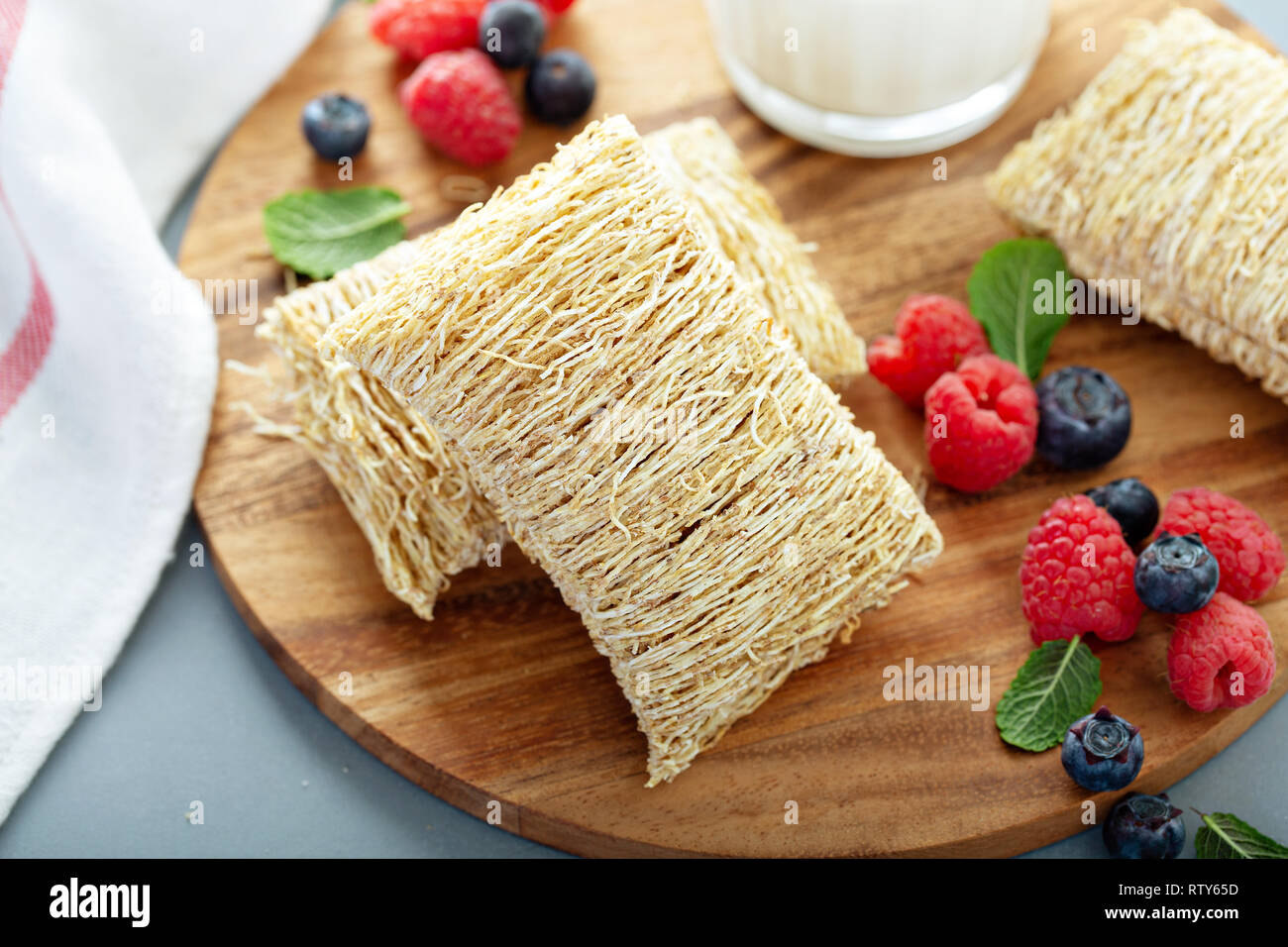 Grandi grani di trinciato accanto al bicchiere di latte e frutti di bosco Foto Stock