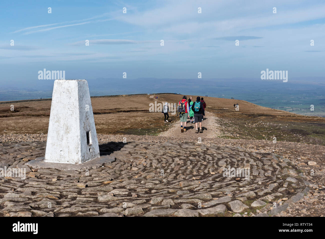 Walkers sul Pendle Hill, Lancashire, Regno Unito, con il vertice punto trig in primo piano. Foto Stock