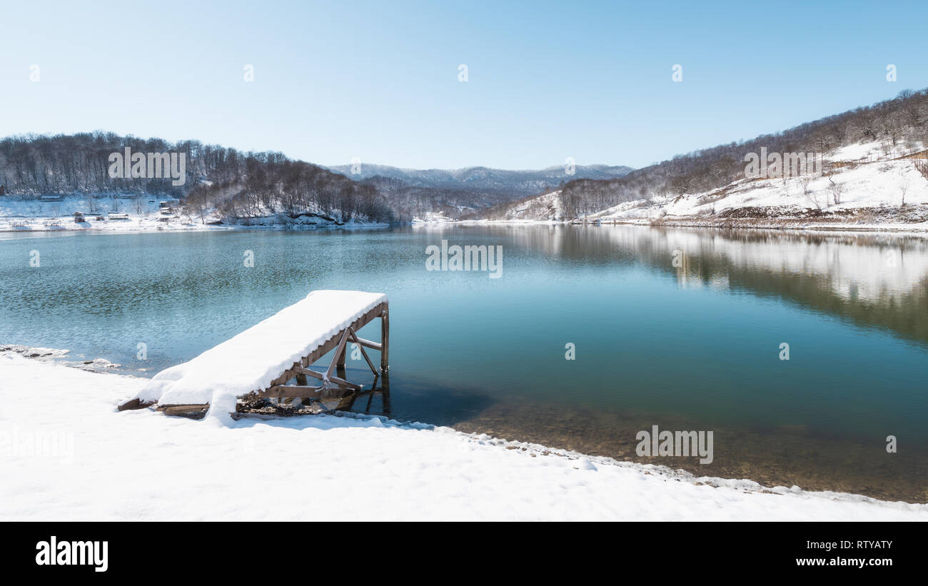 Coperta di neve pier sul lago highland Foto Stock