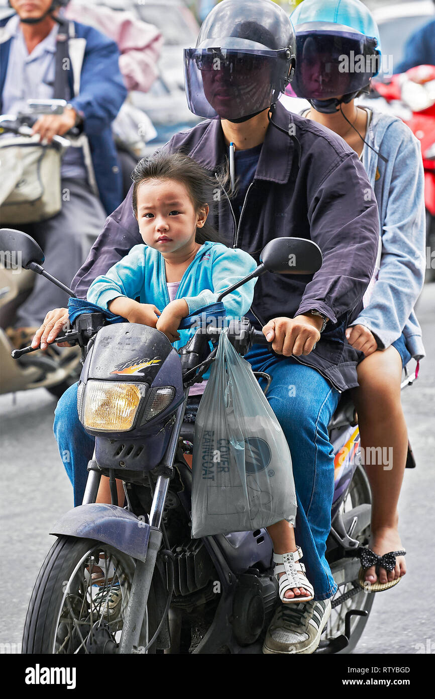 Bangkok, Tailandia - 11 Giugno 2011: una coppia giovane guida su una moto con una giovane ragazza senza indossare il casco in seduta davanti, catturati nel T.R.A. Foto Stock