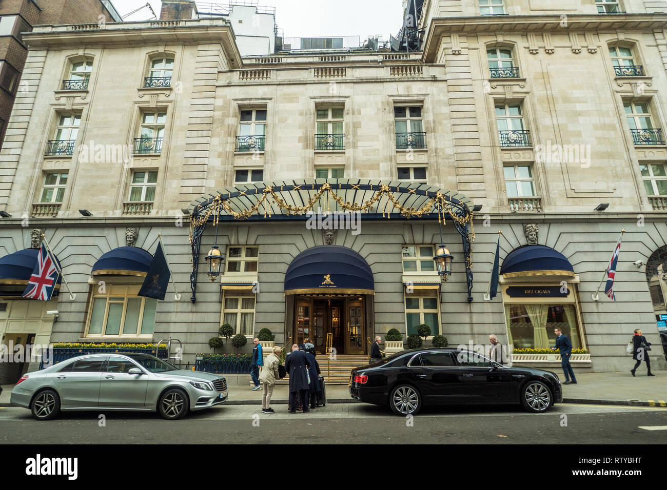 Gli ospiti di essere aiutato con i loro bagagli fuori "The Ritz London' hotel nella zona di Mayfair di Londra. Foto Stock