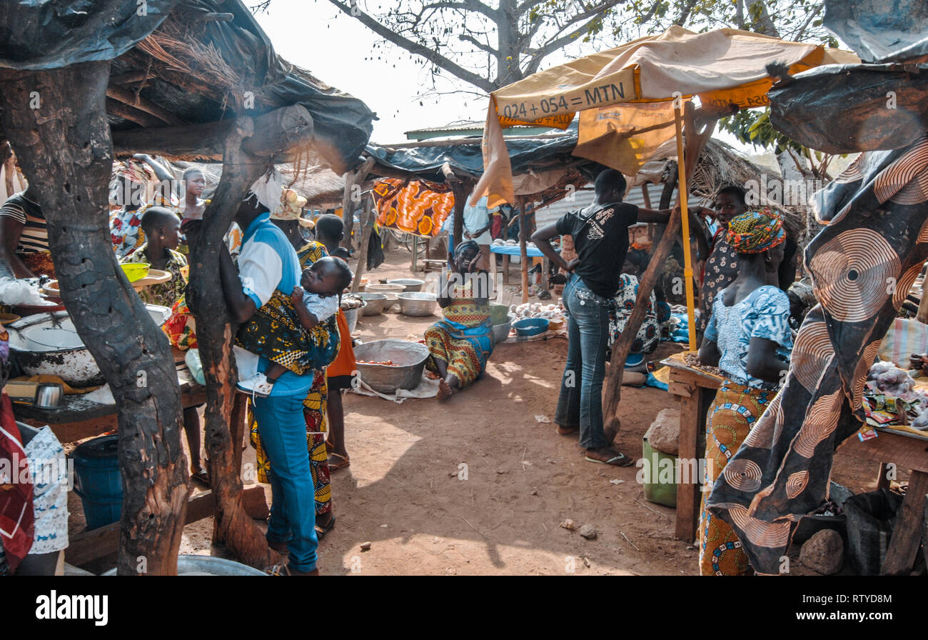 Una bella foto colorata del trafficato mercato agricolo in Kongo Village, nel nord del Ghana. Una donna in medio sta cantando e battendo le mani. Foto Stock