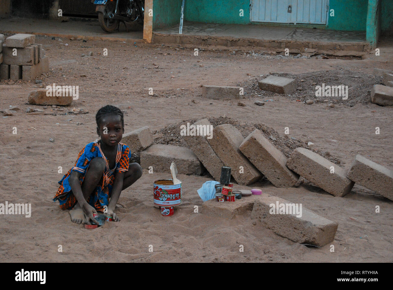 Una foto di una ragazza che indossa tradizionali abiti del Ghana giocando nella sabbia in un locale sito in costruzione Foto Stock