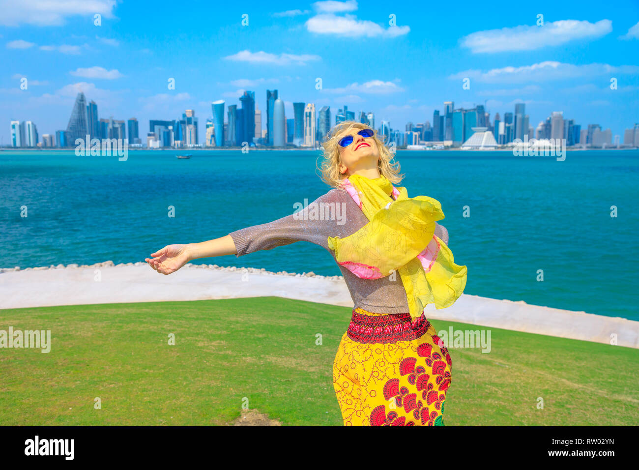 Il Qatar concetto di viaggio. Spensierata donna caucasica enjoyis le opinioni di Doha West Bay. Blonde turistico a Doha Downtown da est Mound-Skyline viewpoint Foto Stock