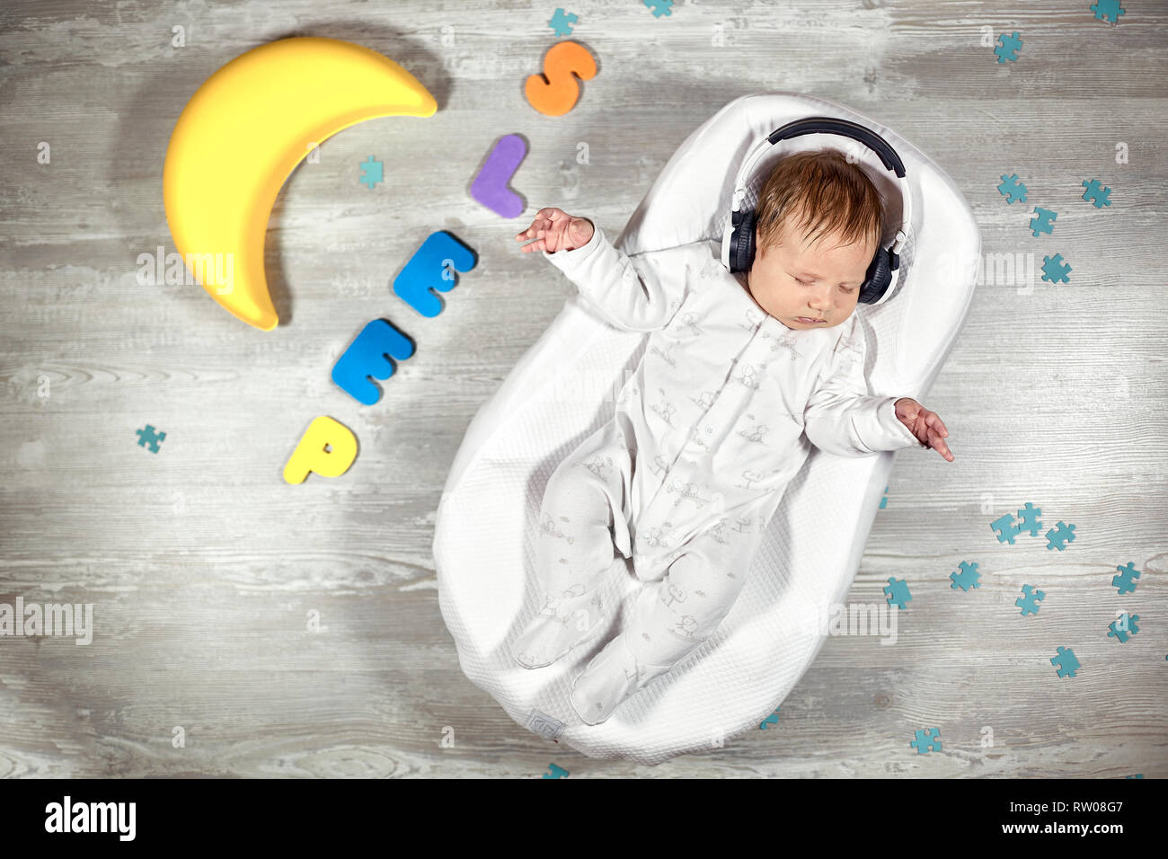 Neonato dorme in una speciale materasso ortopedico Baby cocoon, su un  pavimento di legno variopinto lettere intorno a. La calma e il sonno sano  nei neonati Foto stock - Alamy