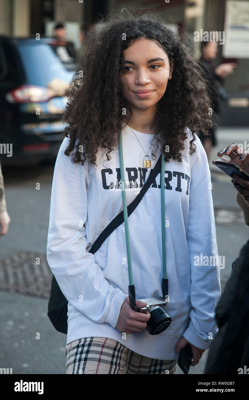 Londra - 15 febbraio 2019: Elegante partecipanti al di fuori di raccolta 180 del filamento per la London Fashion Week. Curly ragazza in una luce bianca e felpa pla Foto Stock