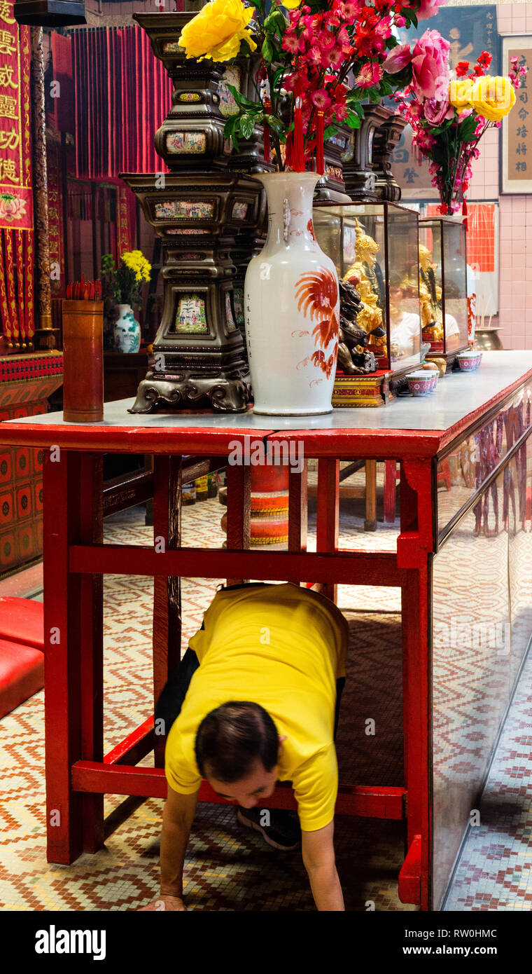 Adoratore di strisciare sotto la tabella davanti all altare per guadagnare il merito e la benedizione, peccato Sze Si Ya Tempio Taoista, Chinatown, Kuala Lumpur, Malesia. Foto Stock