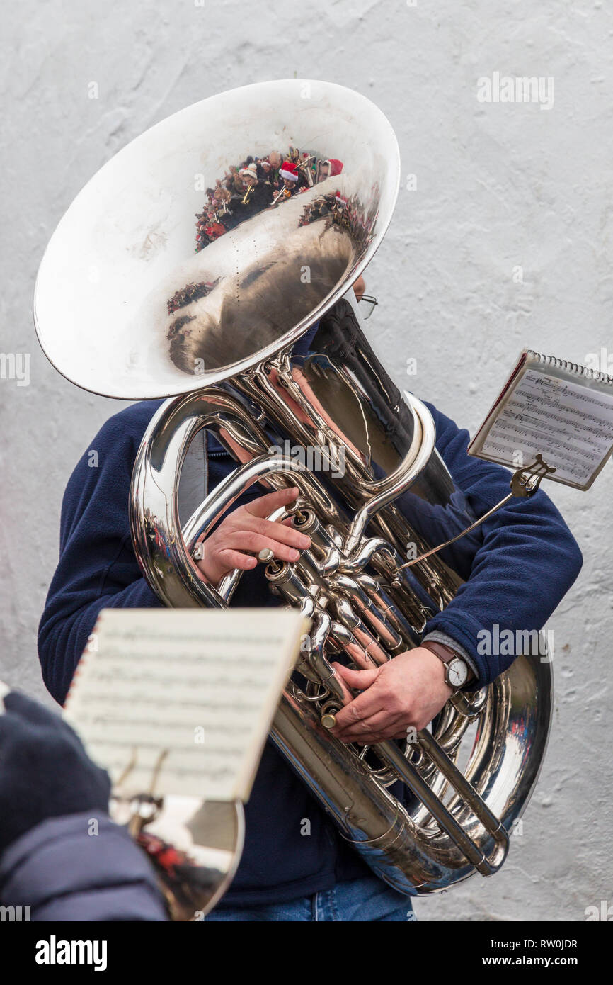 Tubista da Bollington brass band suonare carols sulla mattina di Natale su bianco Nancy. Persone con cappelli di Natale si riflette nella tuba Foto Stock