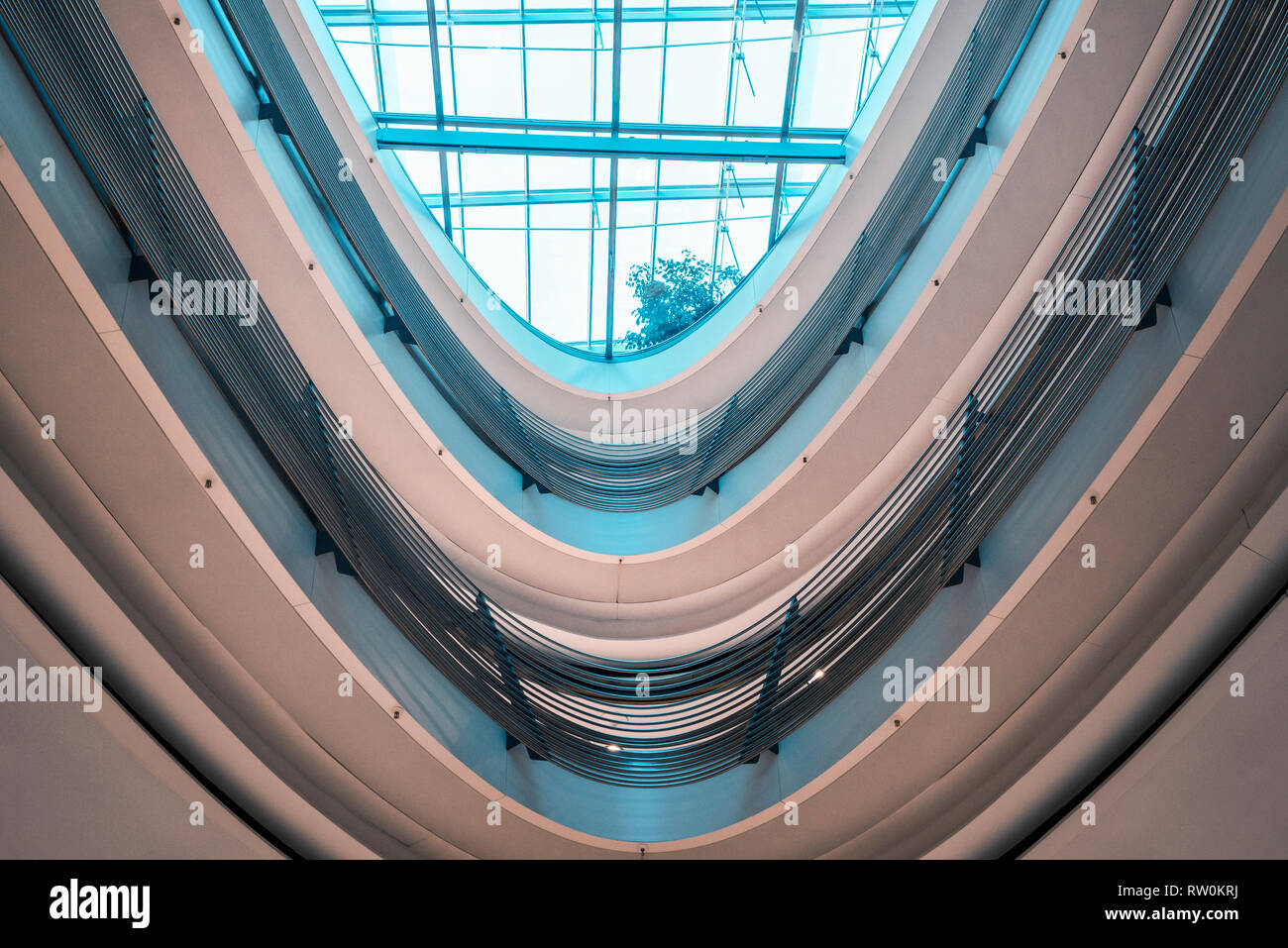 Architettura futuristica con un soffitto in vetro e parapetti a spirale in un moderno centro commerciale, con blu brillante di luce, nella città di Stoccarda, Germania. Foto Stock