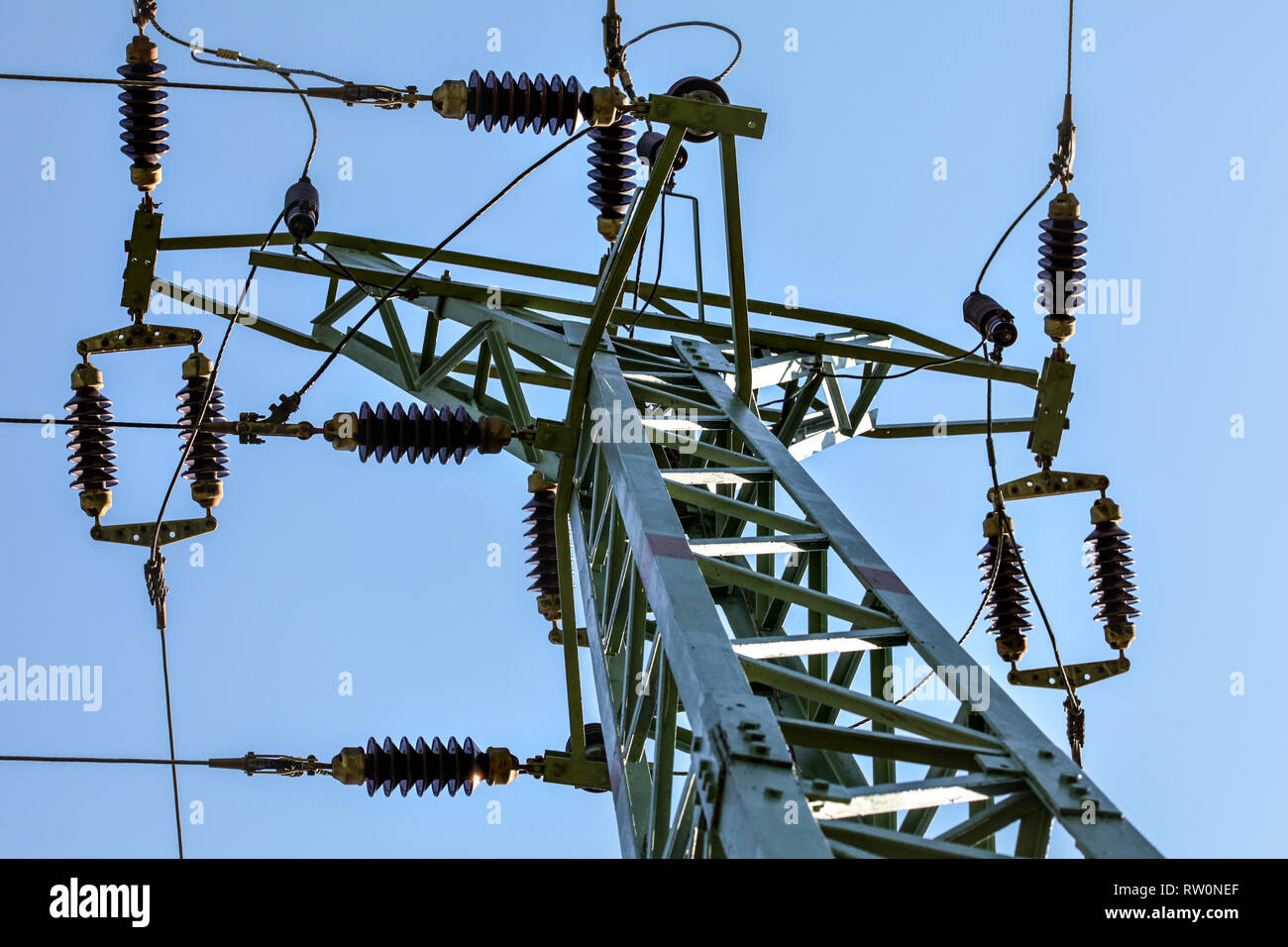 Vista dalla terra al pilone di potenza superiore. I cavi e gli isolatori ceramici visibile contro il cielo blu. Alimentazione astratta l'industria dello sfondo. Foto Stock