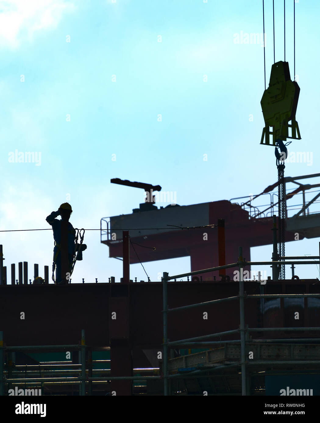 Silhouette di un lavoratore edile al sito in costruzione. Gru Foto Stock