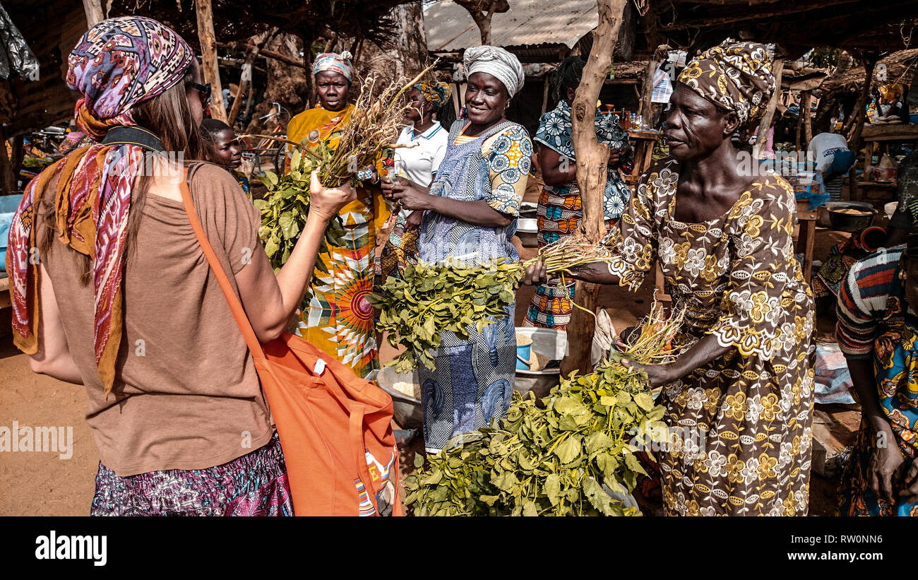 Un turista europeo acquisto di frutti e legumi provenienti da fornitori locali presso il mercato degli agricoltori in Kongo village, Ghana, Africa occidentale Foto Stock