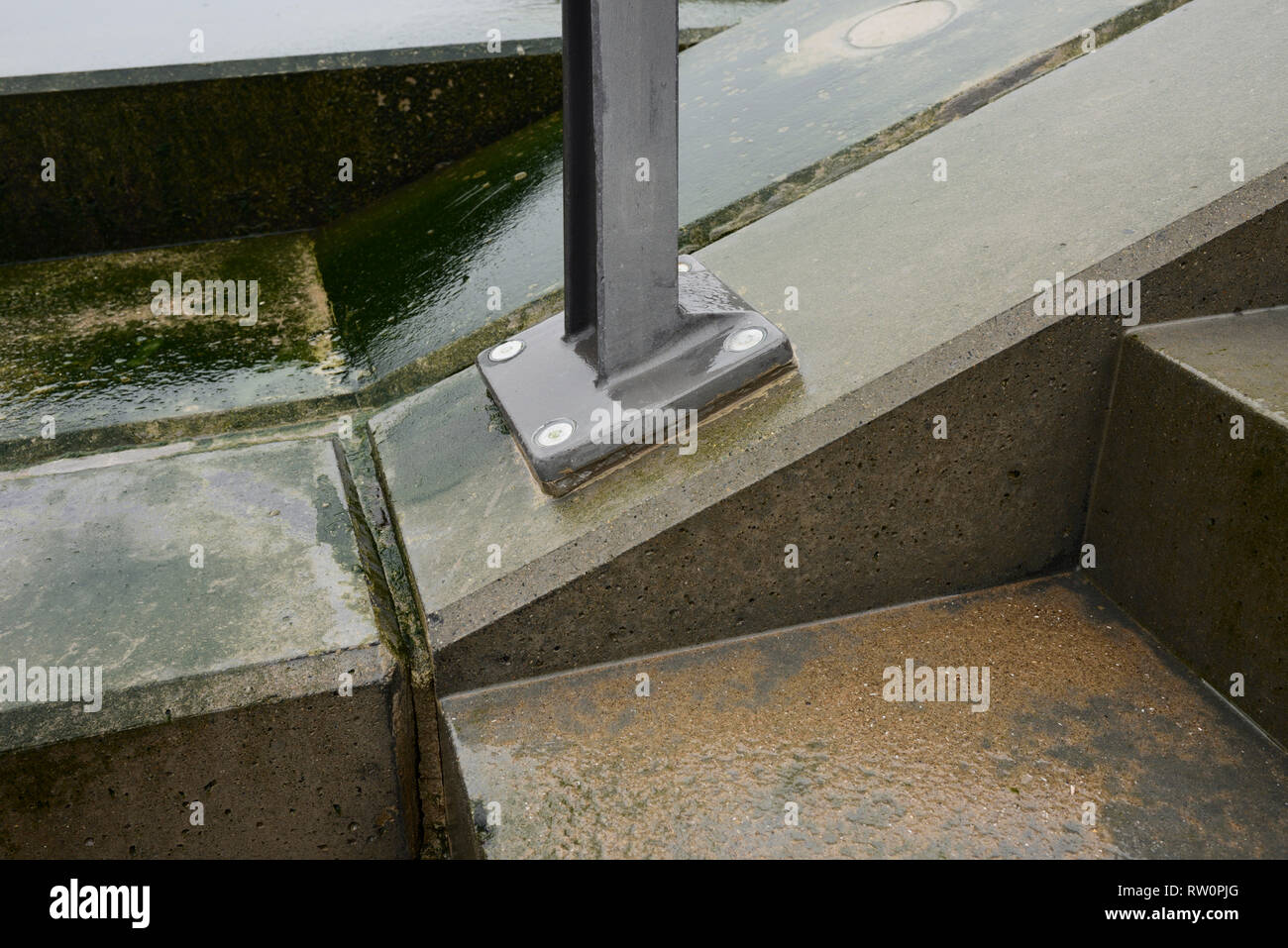 Supporto del corrimano in acciaio resistente alla corrosione imbullonato ad angolo con il calcestruzzo in caso di intemperie ad Anchorsholme, Blackpool, sulla costa di fylde nel lancashire uk Foto Stock