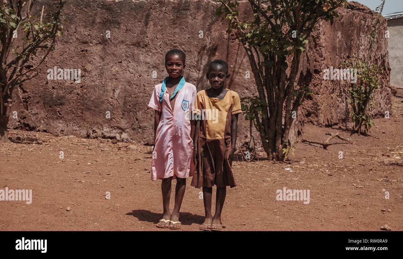 Due bella e felice scuola ghanesi ragazze in posa per la telecamera su una strada di Kongo village, Ghana Foto Stock