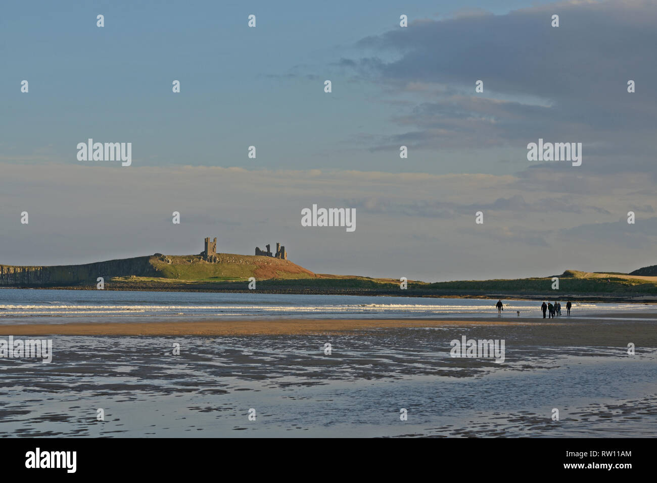 Dunstanburgh Castle a Northumberland con poche persone sulla spiaggia e in una luce attraente Foto Stock