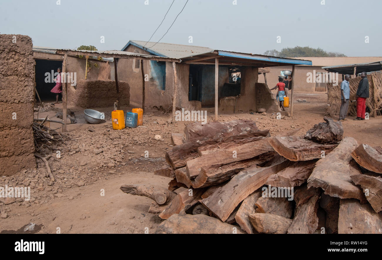 Una bella foto di piccole case e le persone in una piccola strada naturale nelle zone rurali del Ghana. Catasta di legna da ardere è visto in primo piano. Foto Stock