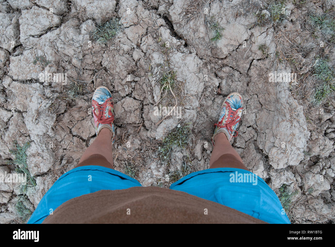 Una foto delle gambe di una donna che indossa sneakers rosso e in piedi sulla massa secca di Mole National Park, il Ghana Foto Stock