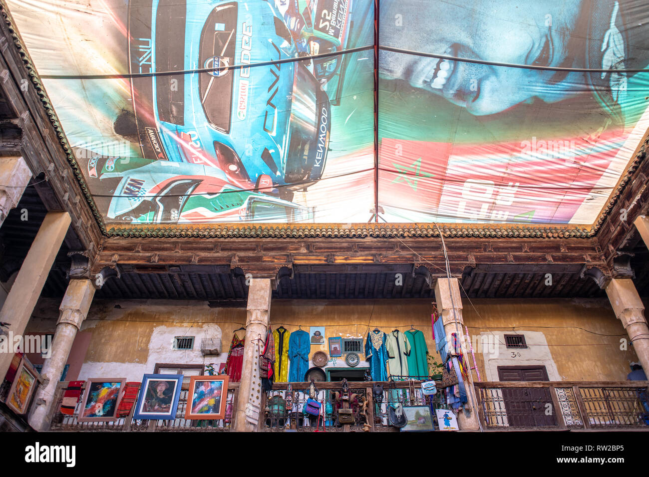 Guardando il tarp con illustrazione della gara marocchino-auto conducente copertura cortile aperto, Marrekech, Marocco Foto Stock