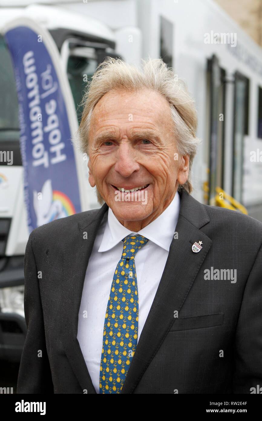 Derek Bell MBE, con il successo di racing driver, con uno della carità della Mobile la cura del cancro di unità, parcheggiata fuori la cattedrale di Gloucester per la s Foto Stock