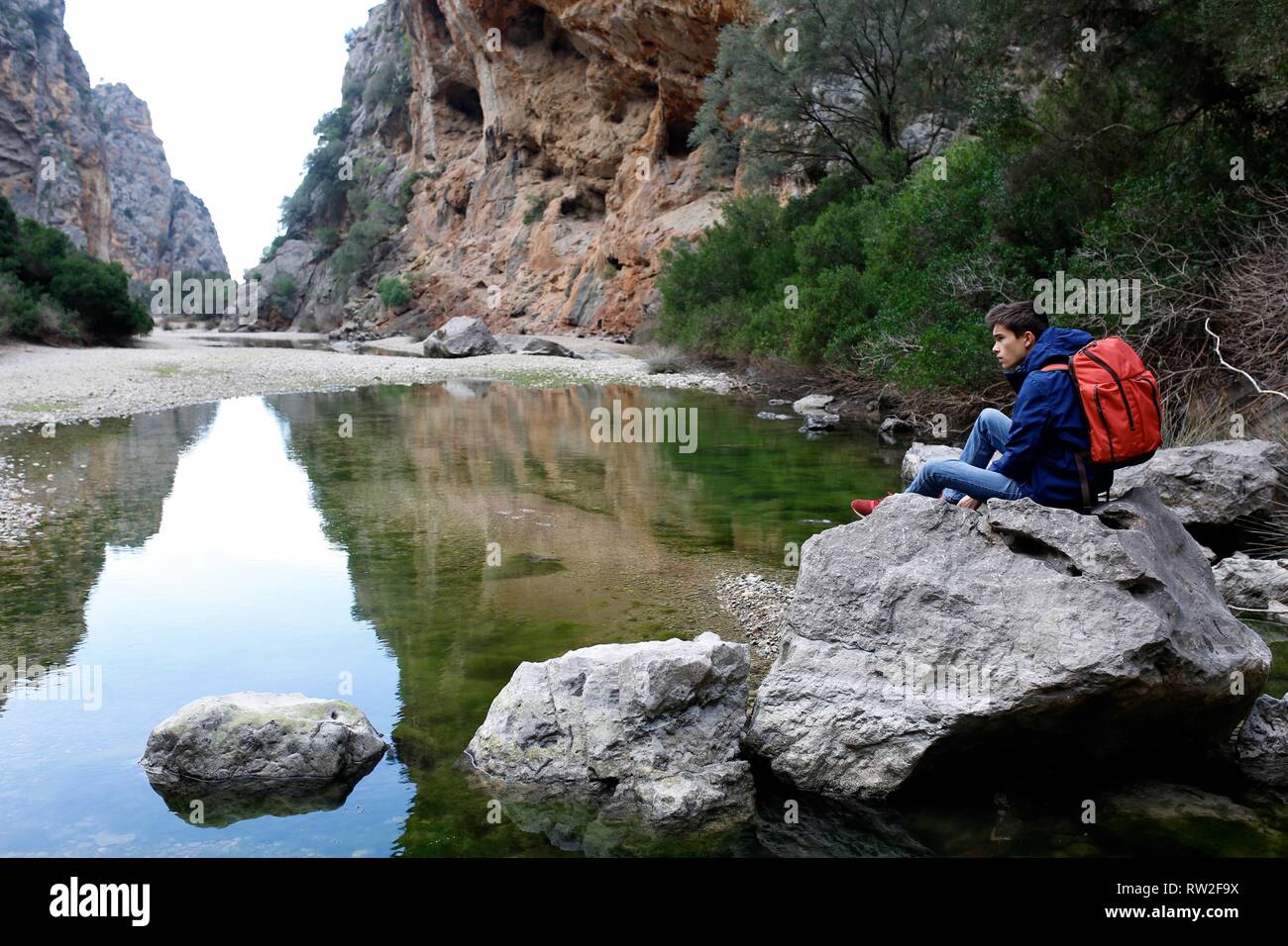Bambino da solo escursionismo seduto vicino a un lago di montagna in appoggio sulla pista Foto Stock