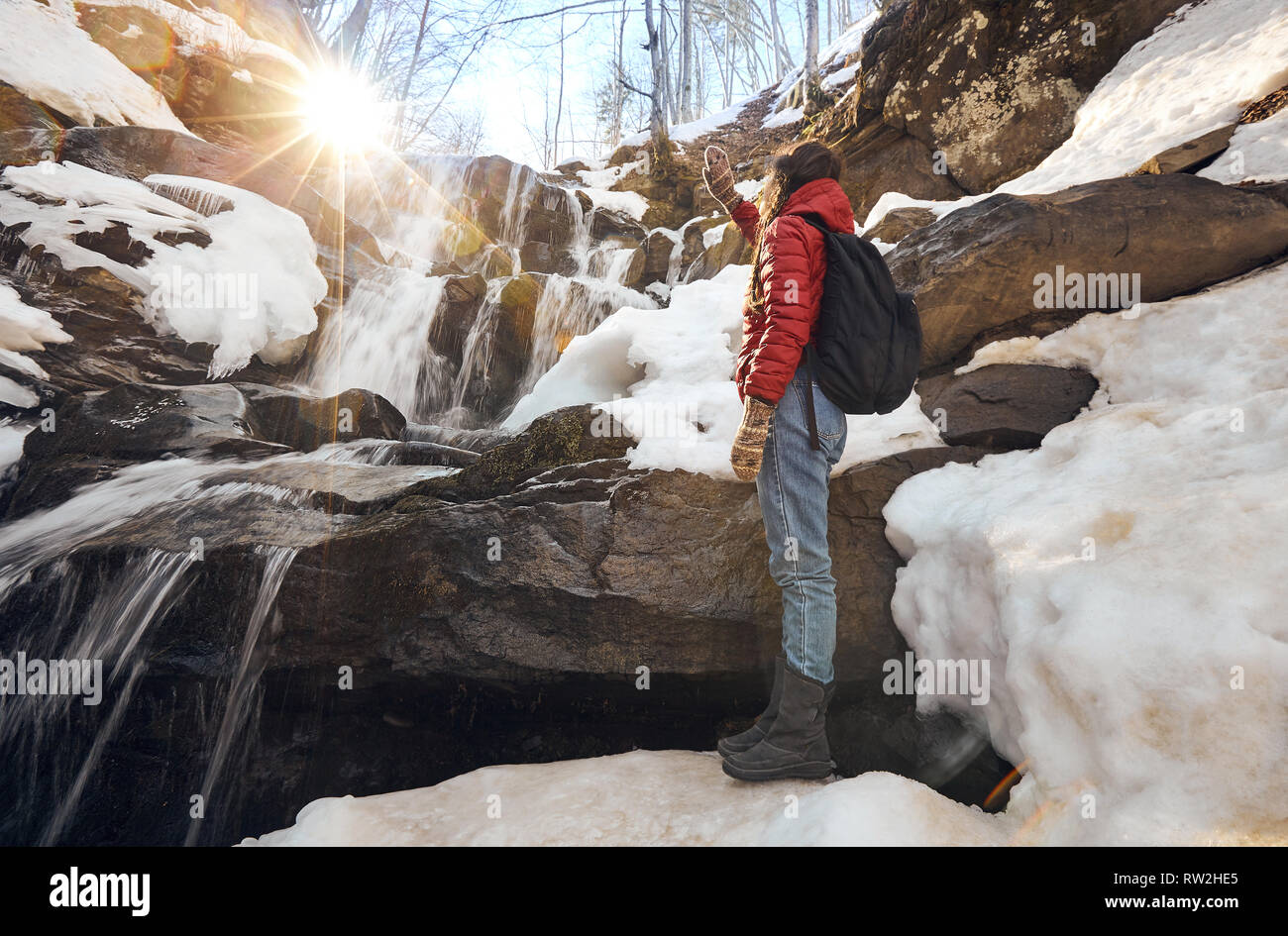 Ragazza guardando a cascata invernale e arancione Sun Foto Stock