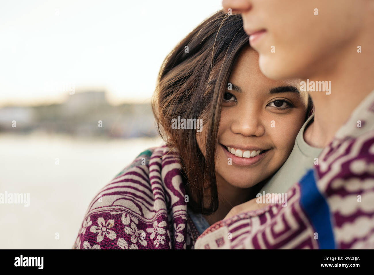 Sorridente giovane donna avvolta in una coperta con il suo fidanzato Foto Stock