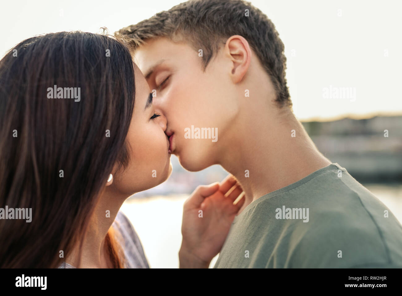 Romantico coppia giovane la condivisione di un bacio al di fuori nel pomeriggio Foto Stock