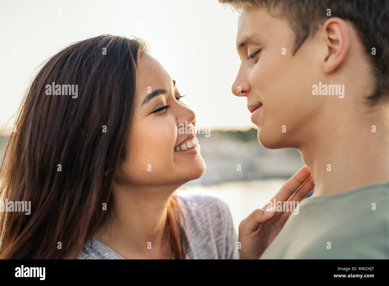 Coppia giovane ridere mentre avvolto in una coperta insieme all'esterno Foto Stock