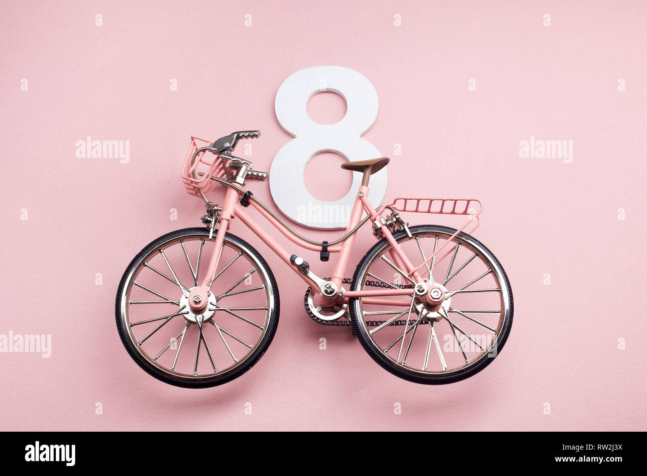 Felice International Womens Day Celebriamo a otto marzo. Numero otto con bicicletta rosa su sfondo rosa Foto Stock