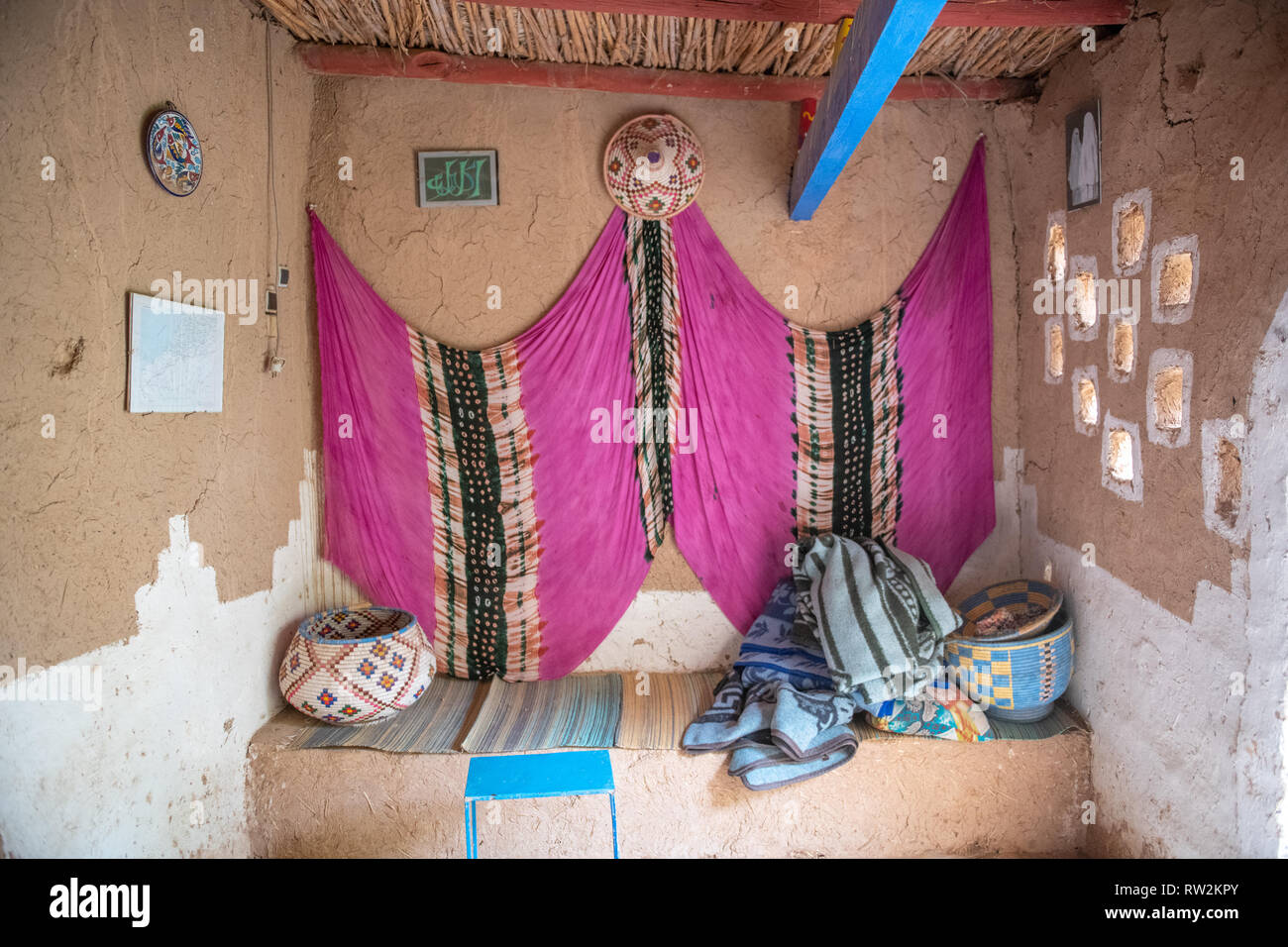 Interno della seduta nook con appeso in tessuto colorato in tradizionali mattoni di fango costruita casa, oasi di Tighmert, Marocco Foto Stock